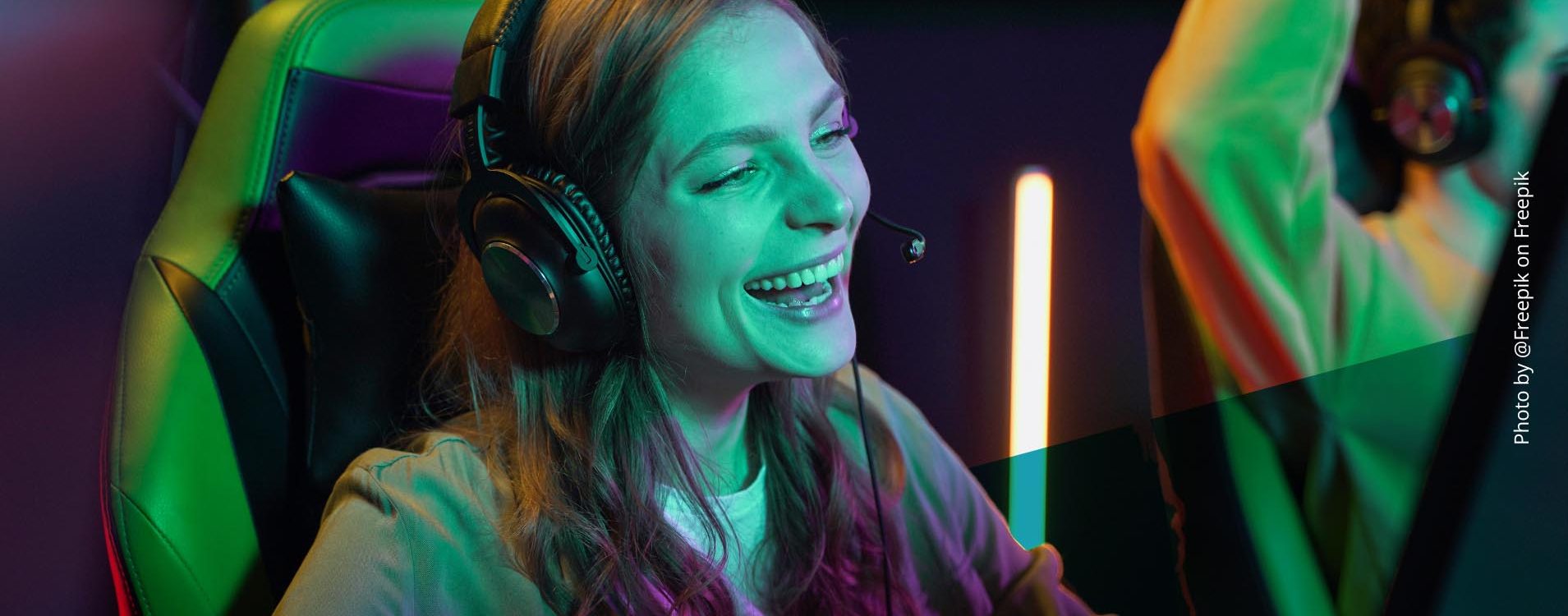 Junge Frau spielt ein Videospiel, trägt Kopfhörer und lacht