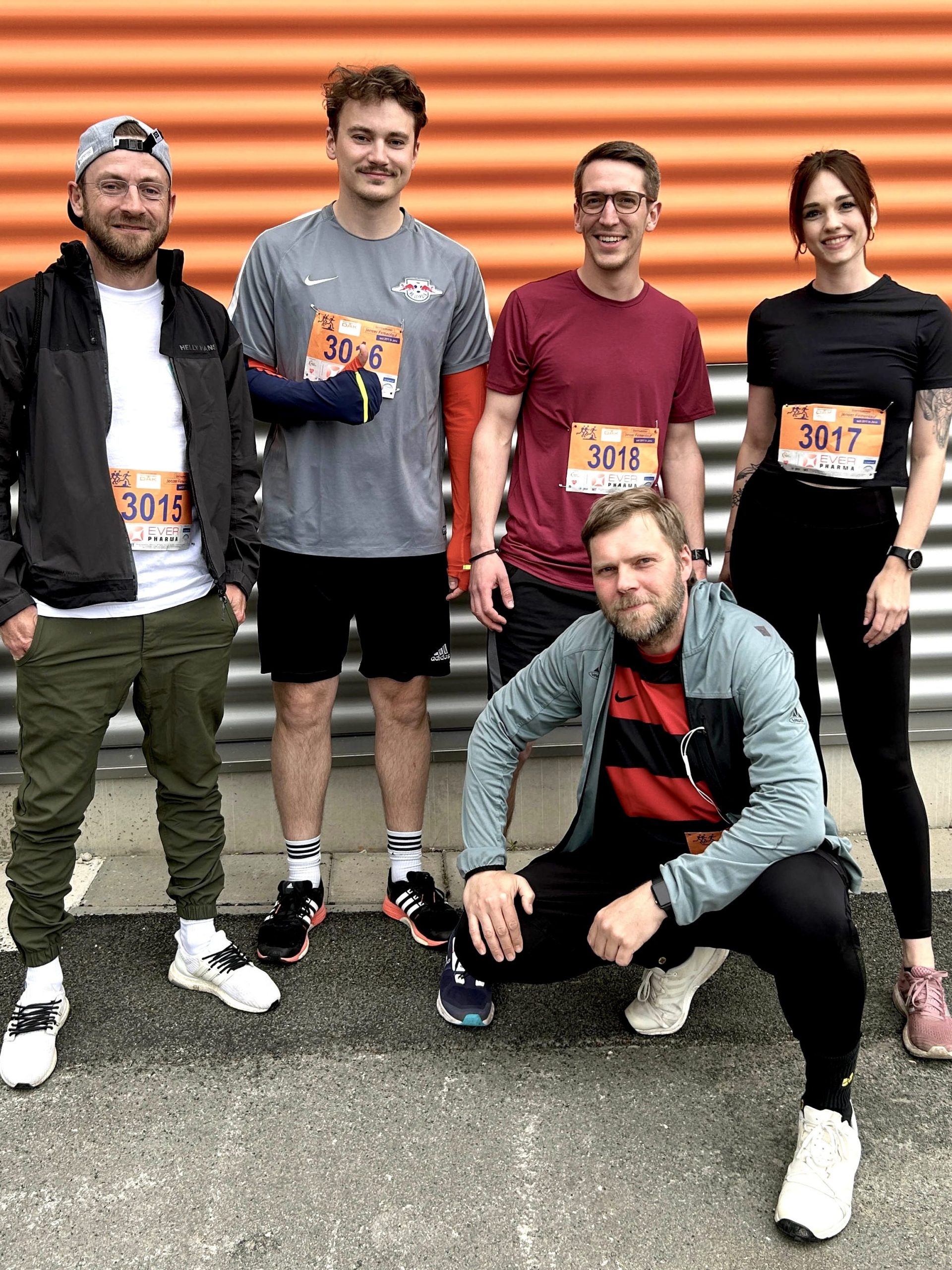 Vier Männer und eine Frau posieren in Sportkleidung