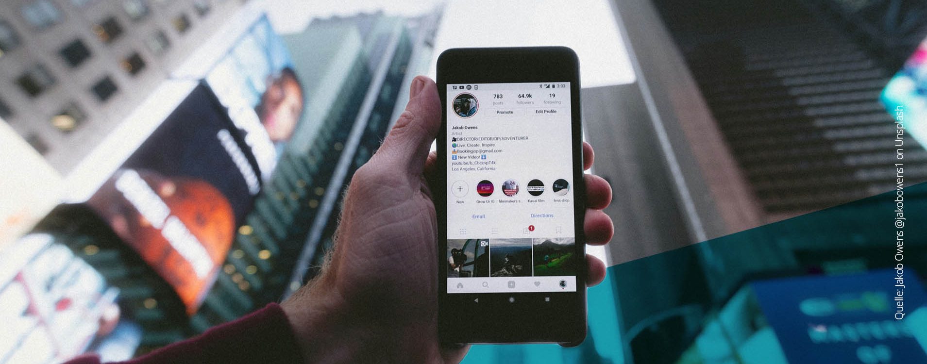 Hand hält ein Handy in die Luft, Hochhäuser im Hintergrund