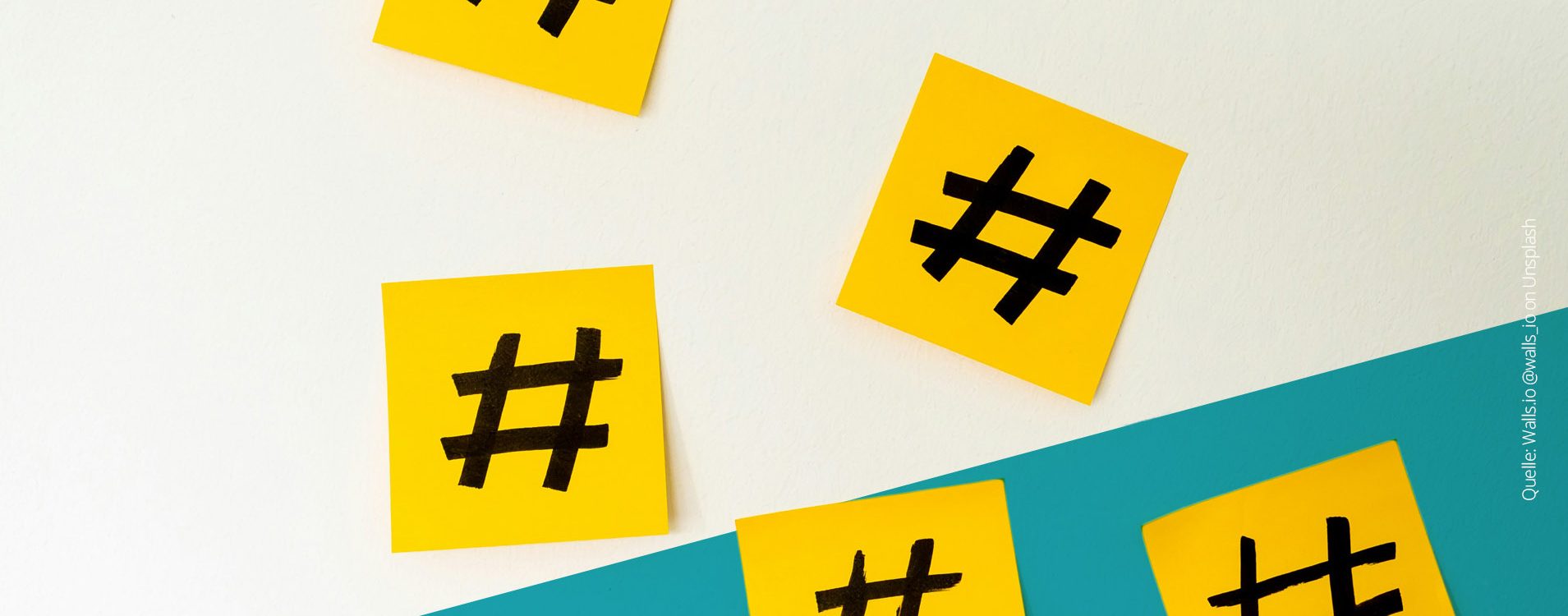 Gelbe Klebezettel mit aufgemalten Hashtags verteilt auf einer weißen Wand