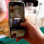 Nahaufnahme von einer Hand, die mit einem Smartphone ein Foto mit der BeReal-App macht