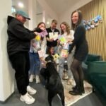 Mitarbeitende der Somengo halten Osterkarten so in den Händen, dass ein Herz gebildet wird und Bürohund Koda möchte auch dabei sein