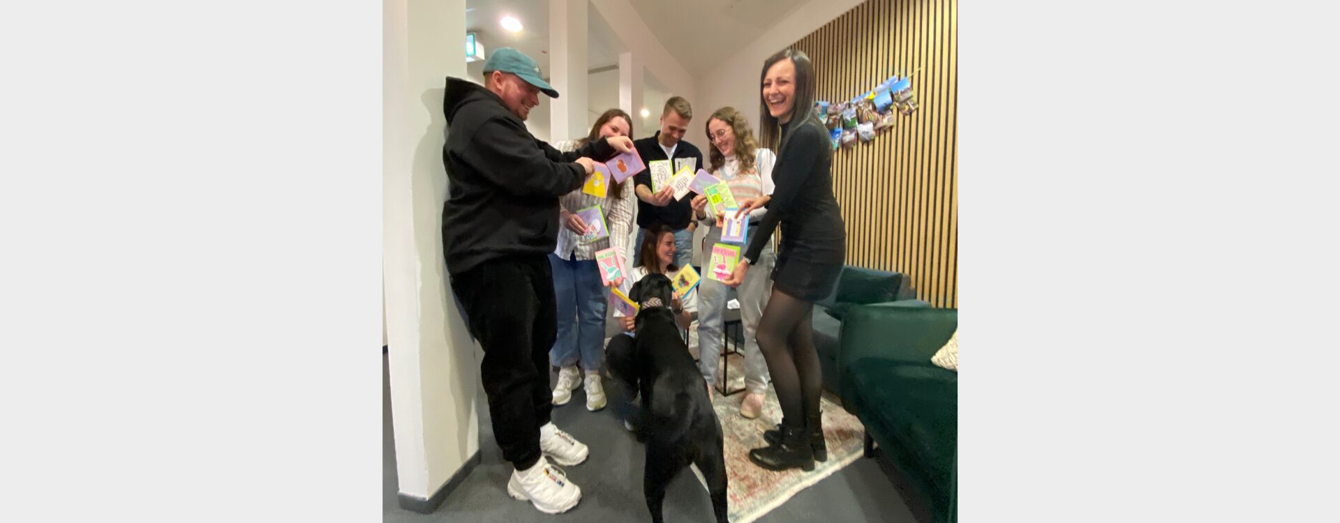 Mitarbeitende der Somengo halten Osterkarten so in den Händen, dass ein Herz gebildet wird und Bürohund Koda möchte auch dabei sein