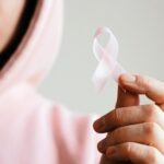 Person in rosa Hoodie hält eine rosa Schleife in der Hand welche für Krebs-Awareness steht